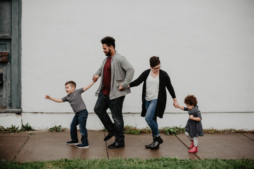 pexels photo 2253879 2253879 A joyful family walking together outdoors, holding hands in a playful and happy moment.